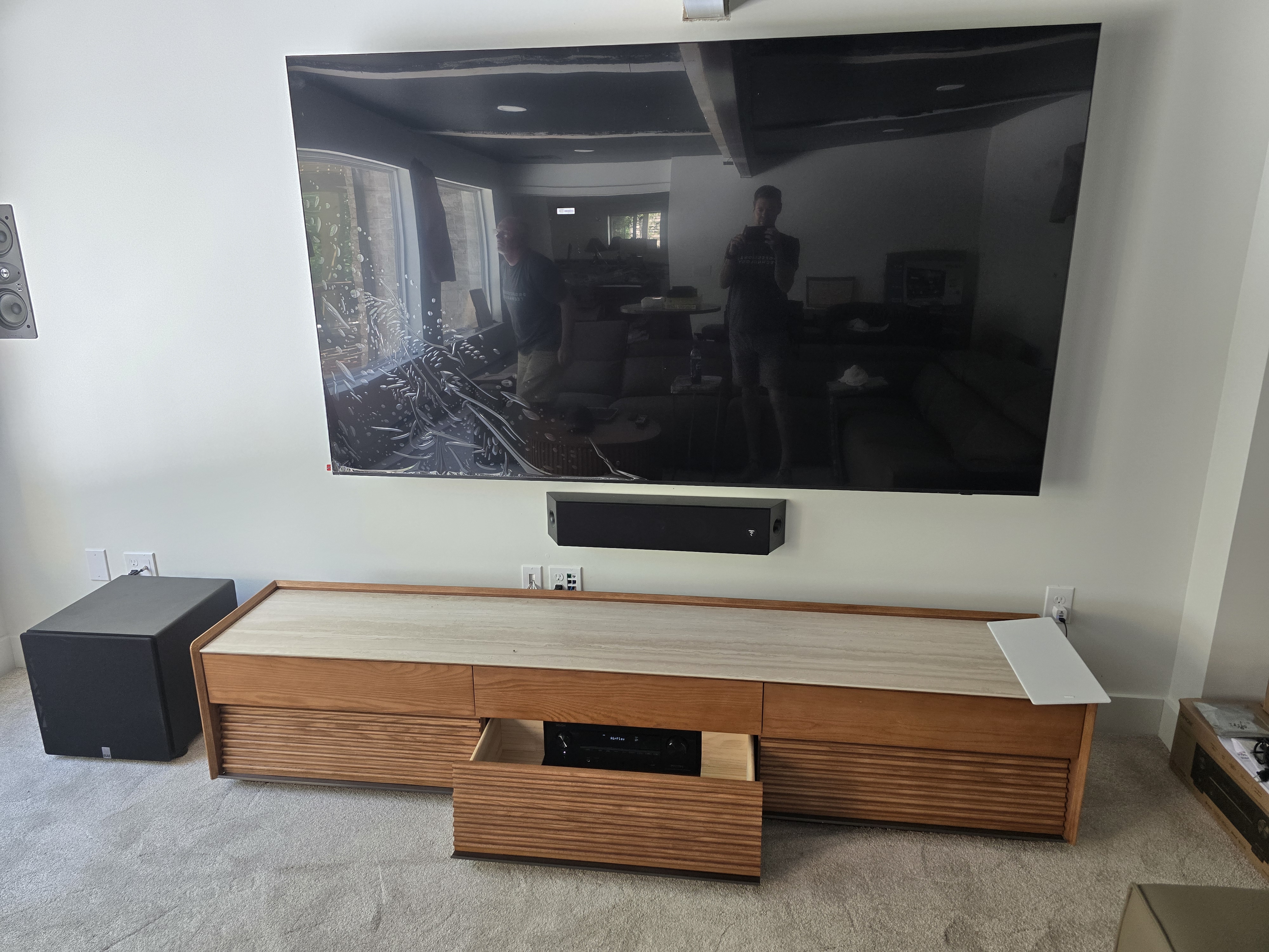 Hudkins Lake House custom AV install — 80-inch QLED wall mount, Focal soundbar, and slat-front oak credenza in a lakeside great room