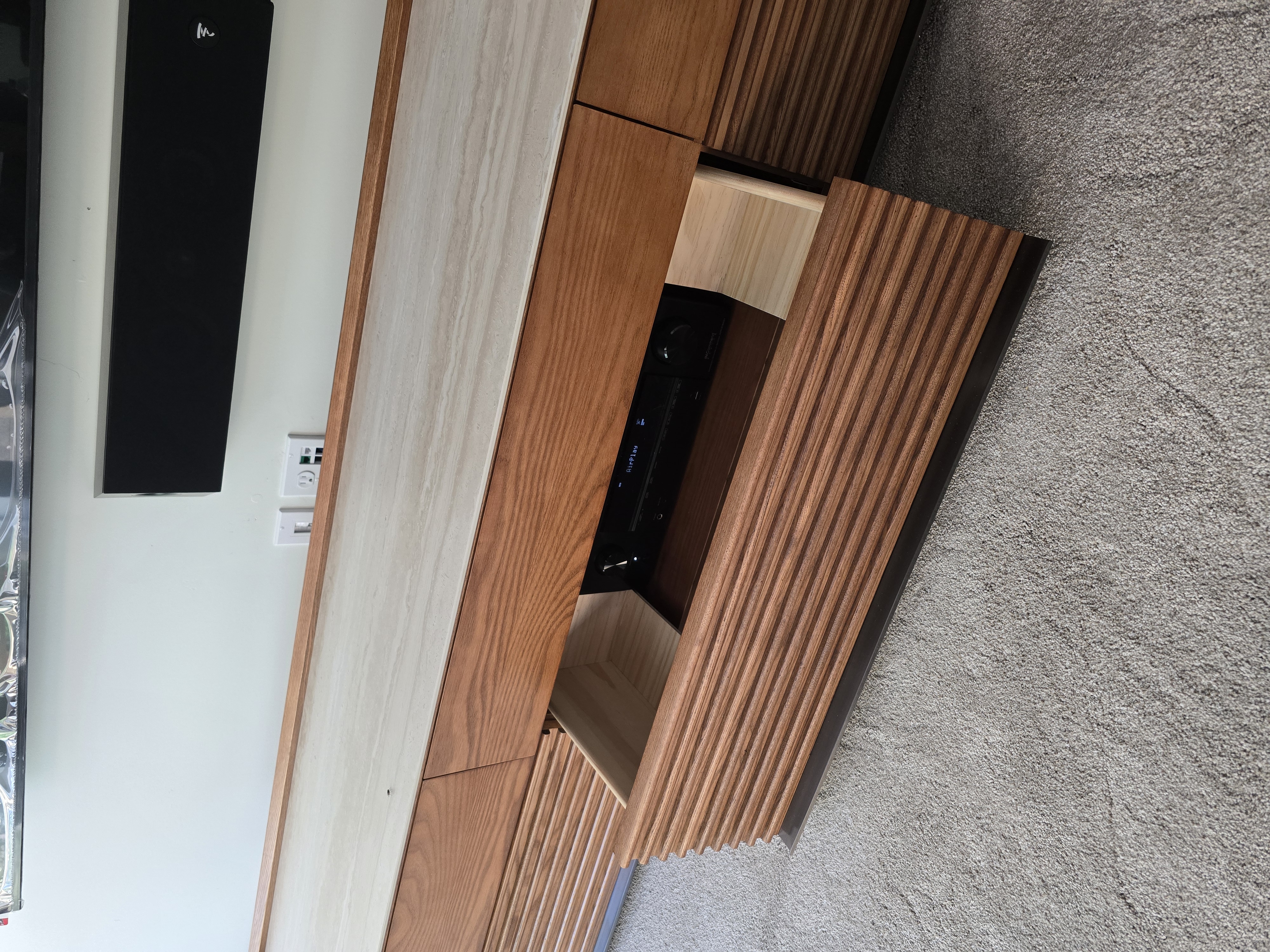 Custom slat-front oak credenza housing the AV receiver and source equipment