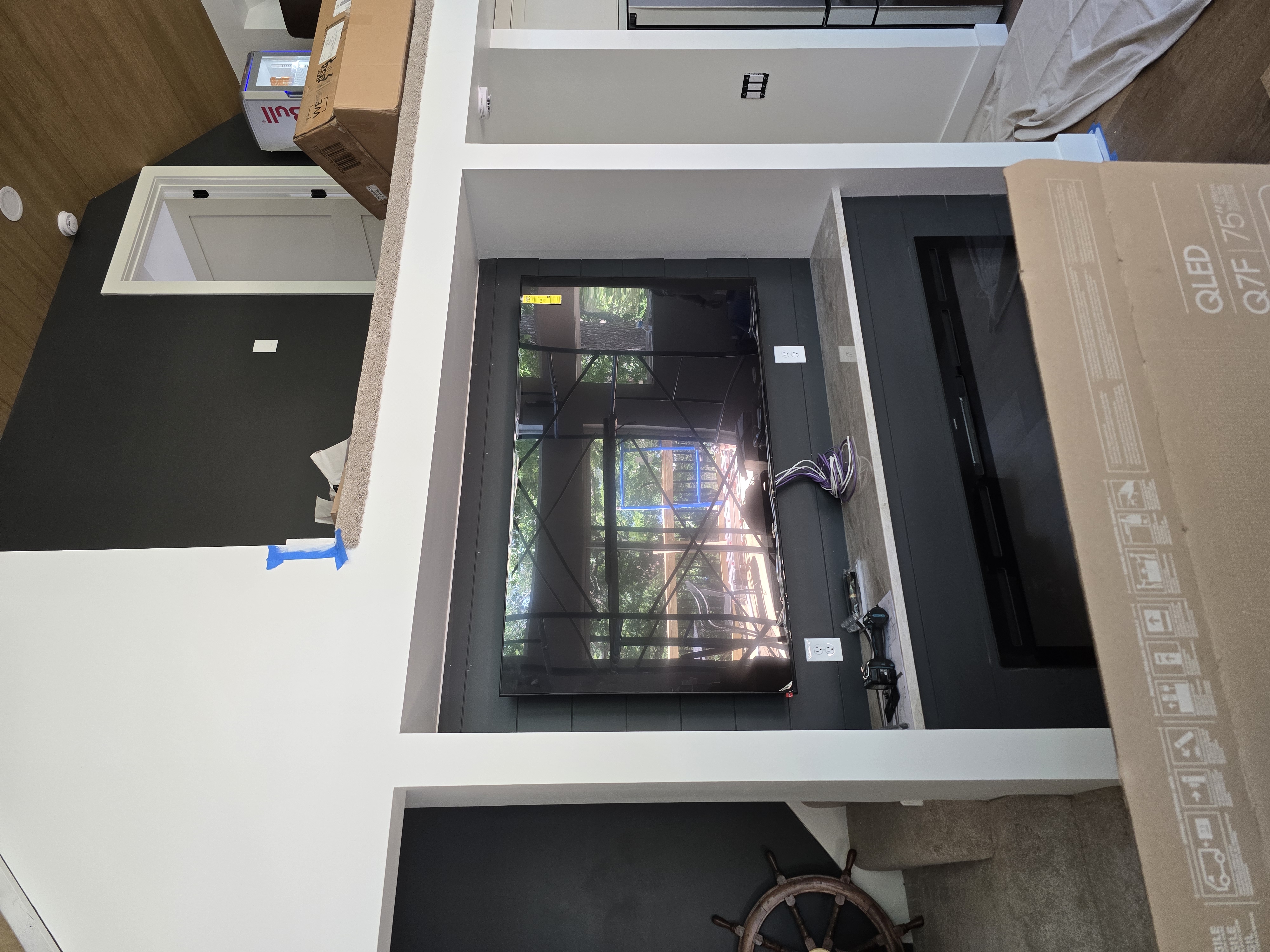 The 75-inch QLED display being mounted mid-install with the Samsung QLED Q7F box visible