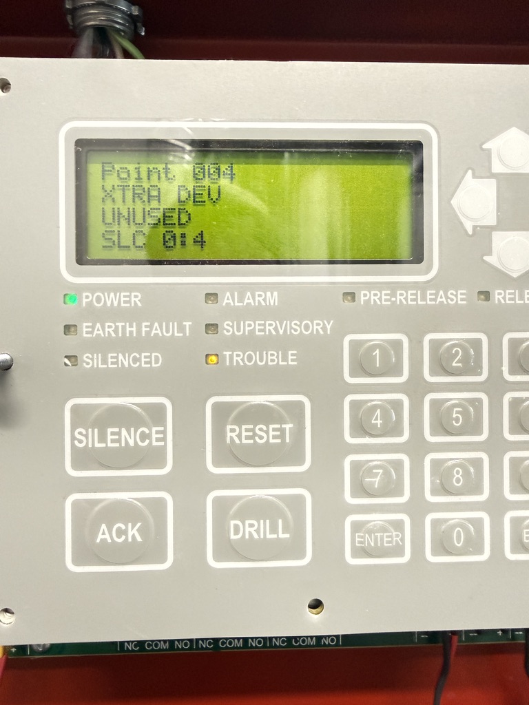 Fire alarm panel keypad close-up — SILENCE, RESET, ACK, DRILL controls with LCD display