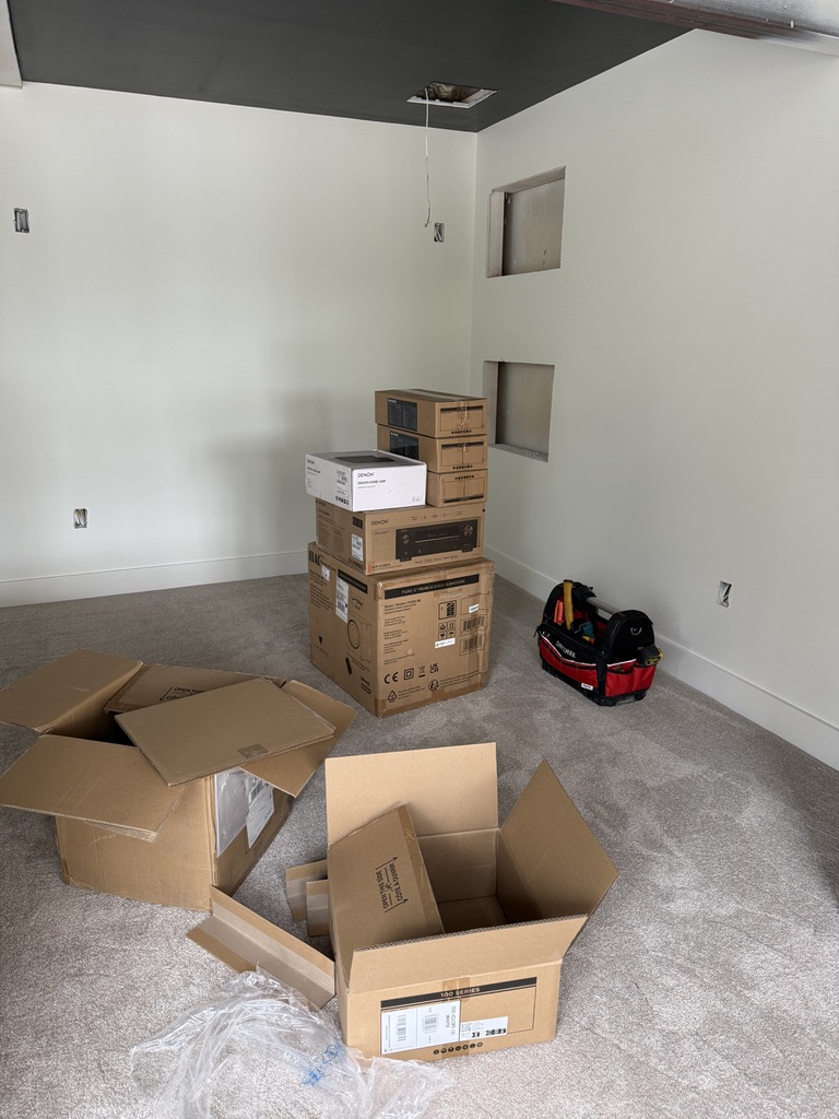 Denon AV receiver and home theater equipment unboxing in a media room mid-install